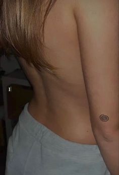 the back of a woman's breast with a small circle tattoo on her left side