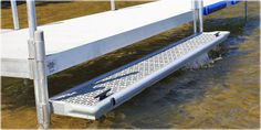 a white bench sitting in the water next to a dock and some blue pipe posts