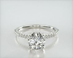 a white gold engagement ring with diamonds on the band and a center stone in the middle