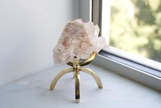 a piece of rock sitting on top of a stand next to a window sill