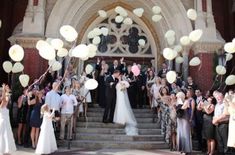 a group of people standing in front of a building with balloons and confetti