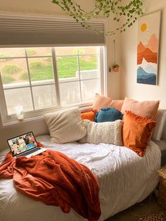 a bed with pillows and blankets on top of it in front of a large window