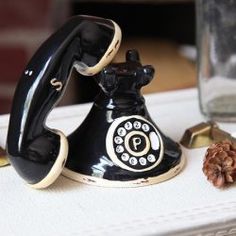 an old fashioned phone sitting on top of a table next to a pinecone