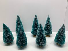 six small blue christmas trees sitting on top of a white table next to each other