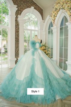 a blue and white wedding dress on display in front of a large window with flowers