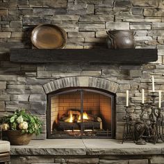 a stone fireplace with candles and plates on the mantle