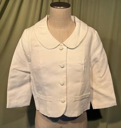 This is a sweet, vintage, cotton jacket or suit jacket from the 1970s or so. Label reads, Sears Fashion, Sears, Roebuck and Co. U.S.A. No size tags. The bust measures 38" with measurements below.  Made of white cotton or cotton blend with a horizontal ribbed texture. It has a button front with 4 fabric covered buttons, 3/4 length sleeves & a large round collar.  There are 2 faux pockets on the front. Slightly boxy shape with the hemline to the waist area. Fully lined. Charming!   The jacket is i Fitted Cotton Cropped Jacket With Button Closure, Tailored Vintage Cotton Outerwear, Vintage Single-breasted Cotton Blazer, Fitted Cream Cotton Blazer, Retro Lapel Collar Blazer For Spring, Vintage Cotton Blazer For Work, Retro Spring Blazer With Lapel Collar, Retro Cotton Blazer For Work, Retro Blazer With Lapel Collar For Spring