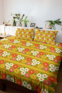 a bed covered in yellow and red flowers next to potted plants on a table