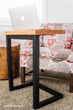 an open laptop computer sitting on top of a wooden table in front of a couch