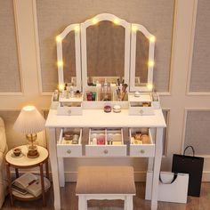 a white vanity with lights on it and a stool in front of the mirror that is open