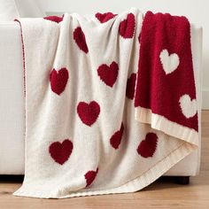 a red and white blanket with hearts on it is sitting on the floor next to a couch