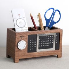 a wooden clock and pen holder with various items in it