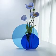 three flowers in a blue vase on a white table