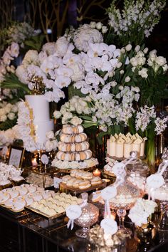 a table topped with lots of desserts and white flowers on top of each other