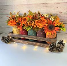 an arrangement of sunflowers and pine cones in mason jars on a wooden stand