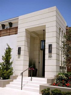 a white house with steps leading up to the front door and flowers in planters