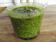 a glass filled with green liquid sitting on top of a wooden table