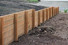 a wooden fence is lined with mulch in the middle of a garden bed area