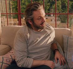 a man sitting on top of a couch next to a woman in front of a window