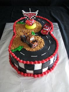 a birthday cake made to look like a race track with cars and trucks on it