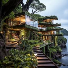 the house is built on top of a cliff by the water and has stairs leading up to it