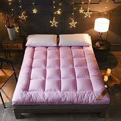 a bed that has some lights on the headboard and pillows in front of it