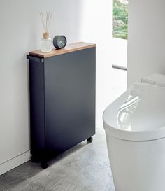 a white toilet sitting next to a black cabinet in a bathroom with a wooden top