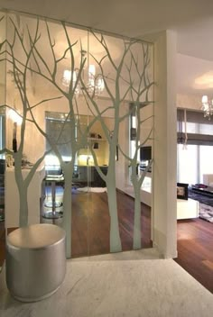 a living room with white walls and trees on the glass wall in front of it