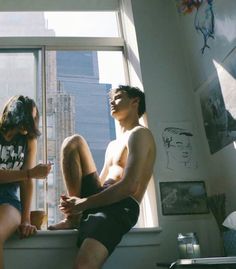 two people sitting on a window sill looking out the window