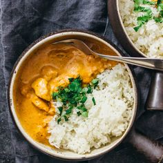 two bowls filled with rice and curry on top of a cloth next to a spoon