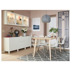 a dining room table with white chairs and an area rug in front of the window