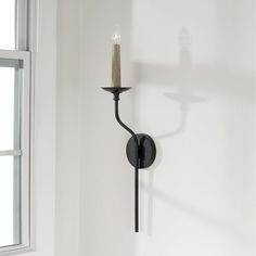 a candle is lit on the wall next to a window in a room with white walls