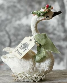 a white duck with a green ribbon and a tag on it's neck sitting on a table