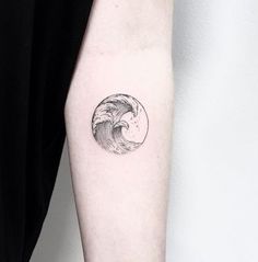 a black and white photo of a wave tattoo on the left inner arm, with an inked circle in the middle