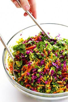 a person is cutting into a salad in a glass bowl