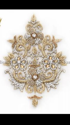 a gold and white brooch with crystal stones