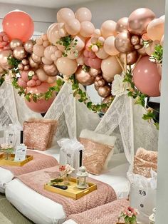 a room filled with lots of pink and gold balloons