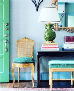 two chairs and a table in front of a green door with a lamp on it