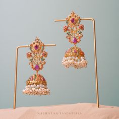 Emanate luxury and royalty in our Sara Earrings that can elevate any ensemble! A vibrant hued nauratan pair of earrings dispersed with brilliant stone work and is balanced with pearl moti clusters. Approximate earrings length is 3.5". Gold-plated on high-quality brass as base metal. Made by order. Kindly allow 5-7 weeks for the delivery of this item. For custom or urgent requests, please contact support@alacouture.com. *Please Note: The multi-colored beadwork might be slightly varying in pattern Jeweled Chandbalis For Reception And Festivals, Jeweled Pearl Earrings For Festivals, Jeweled Earrings For Festivals, Jeweled Pearl Earrings For Festive Occasions, Jeweled Bridal Earrings For Reception And Festivals, Fusion Kundan Multi-stone Earrings, Fusion Style Multi-stone Earrings For Festive Occasions, Festive Fusion Style Jeweled Jhumkas, Festive Fusion Jeweled Jhumkas