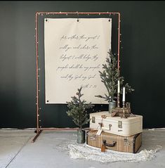 two suitcases and a christmas tree in front of a sign with writing on it