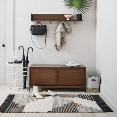 a coat rack with umbrellas and other items on it in a white room next to a door