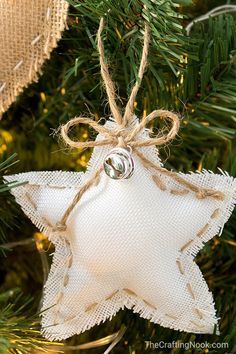 a white star ornament hanging from a christmas tree with burlap and twine