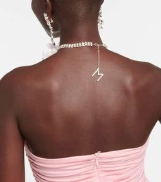 the back of a woman's neck wearing a pink dress with a diamond necklace on it