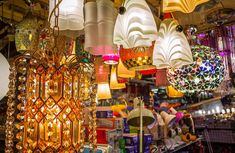 many lamps are hanging from the ceiling in a store with other items on display behind them