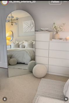 a bedroom with a large mirror and white furniture