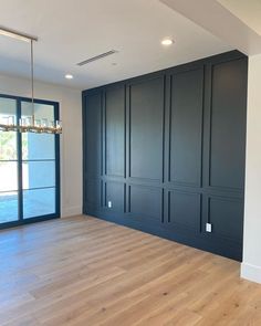 an empty room with wood flooring and black painted walls, along with sliding glass doors