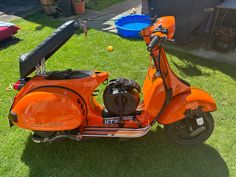 an orange scooter is parked in the grass