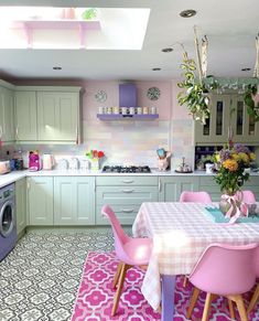 a kitchen with green cabinets and pink chairs on the table in front of the washer