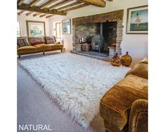 a living room filled with furniture and a fire place next to a stone fireplace surrounded by wooden beams