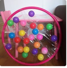 a pink plastic chair with colorful balls in the center and on top of it is a toy table